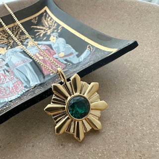 Amelia Sunray Pendant with emerald green crystal on a gold chain, showcasing a stunning sunray design.