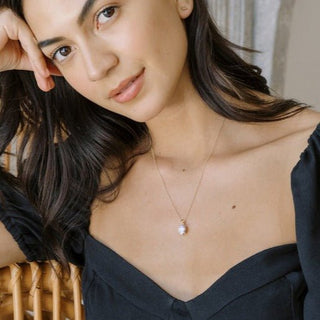 Model showcasing a dainty Confection Necklace with a sparkling oval crystal pendant, perfect for layering with outfits.