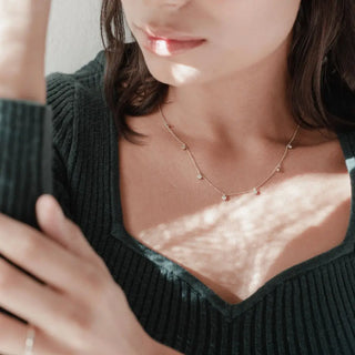 A woman wearing a crystal stardust necklace, showcasing its delicate shimmer against a cozy sweater backdrop.