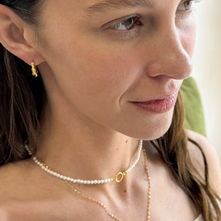 Close-up of a woman wearing the Estelle Pearl Necklace and gold earrings, showcasing effortless elegance.