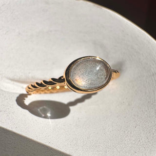 Dainty Nebula Labradorite ring with an oval stone set in a twisted gold band, showcasing its magical color-shifting glow.