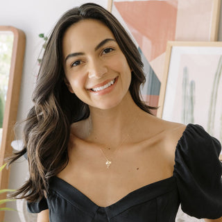 Smiling woman wearing a 14k gold Magic Charms necklace, showcasing cute charm design in a stylish setting.