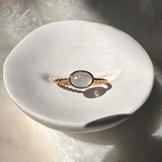 Dainty Nebula Labradorite Ring on a sculptural white dish, showcasing its magical color-shifting glow.