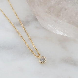 Petite solitaire necklace featuring a tiny cubic zirconia charm on a delicate gold chain.