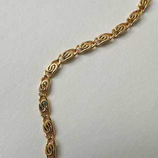 Close-up of the Snail Chain Necklace featuring whimsical spiraled gold links on a neutral background.