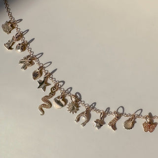 Delicate gold charm bracelet featuring various tiny charms like cats, stars, and shells for personalized jewelry.