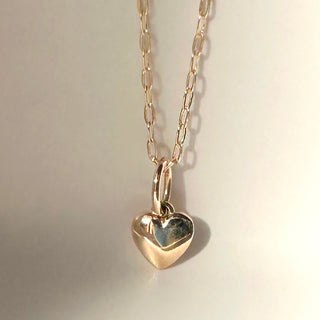 Solid 14k gold tiny puffy heart charm pendant on a delicate chain, perfect for personalizing jewelry.