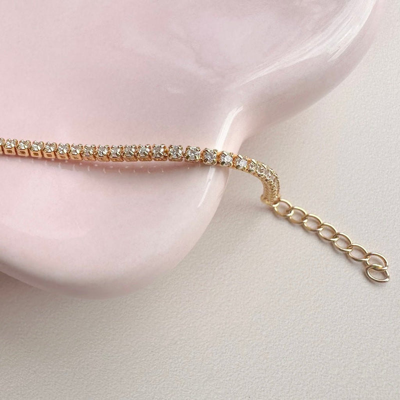 Elegant tennis chain bracelet with 1.6mm crystals on a pink dish, featuring a 1" extender for a perfect fit.
