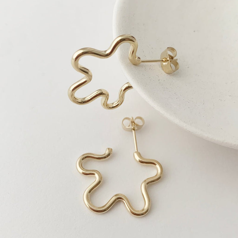 Whimsical gold floral hoop earrings with a playful design, showcasing femininity and style.